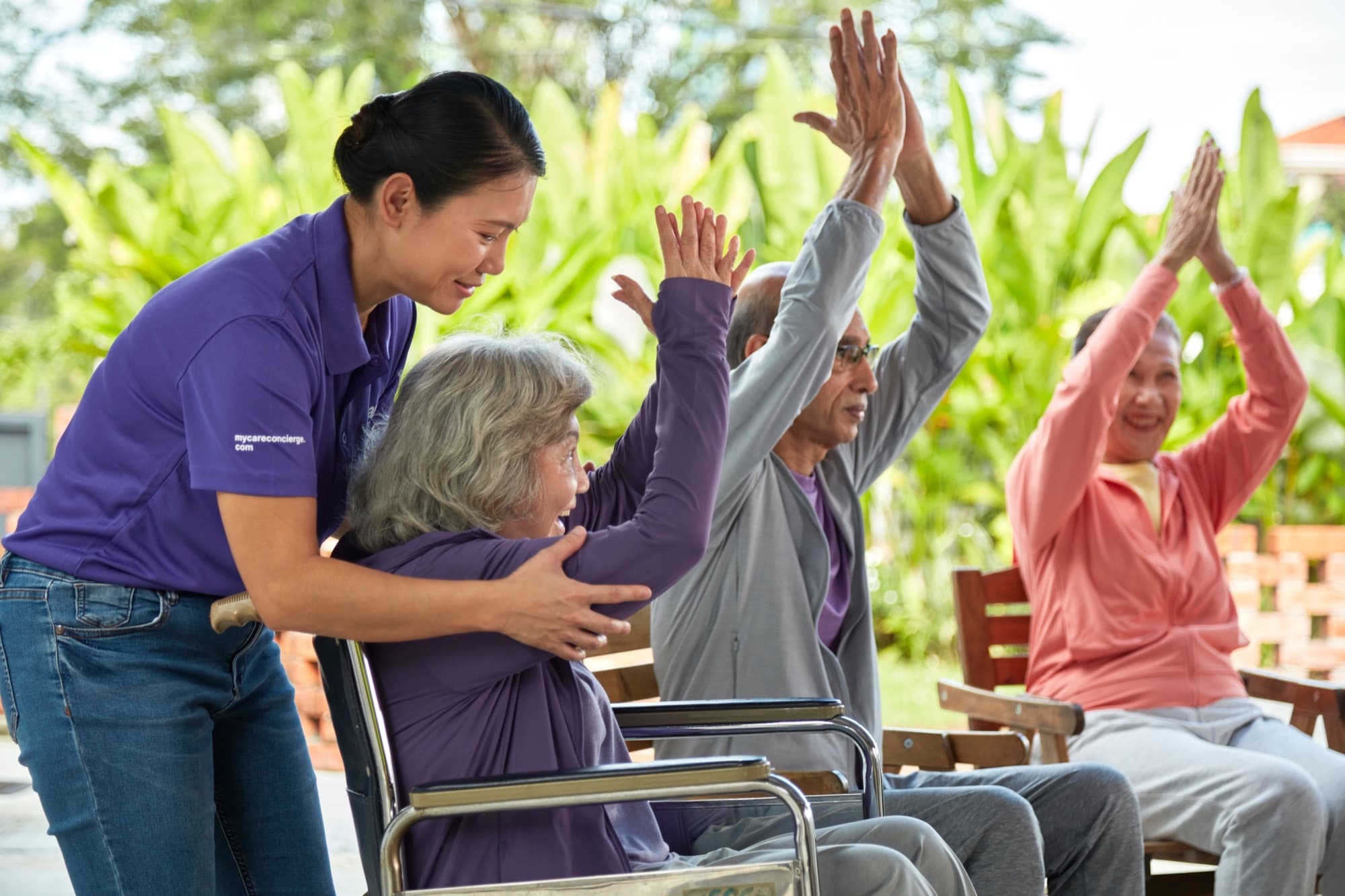Caregiver assisting senior in outdoor group exercise