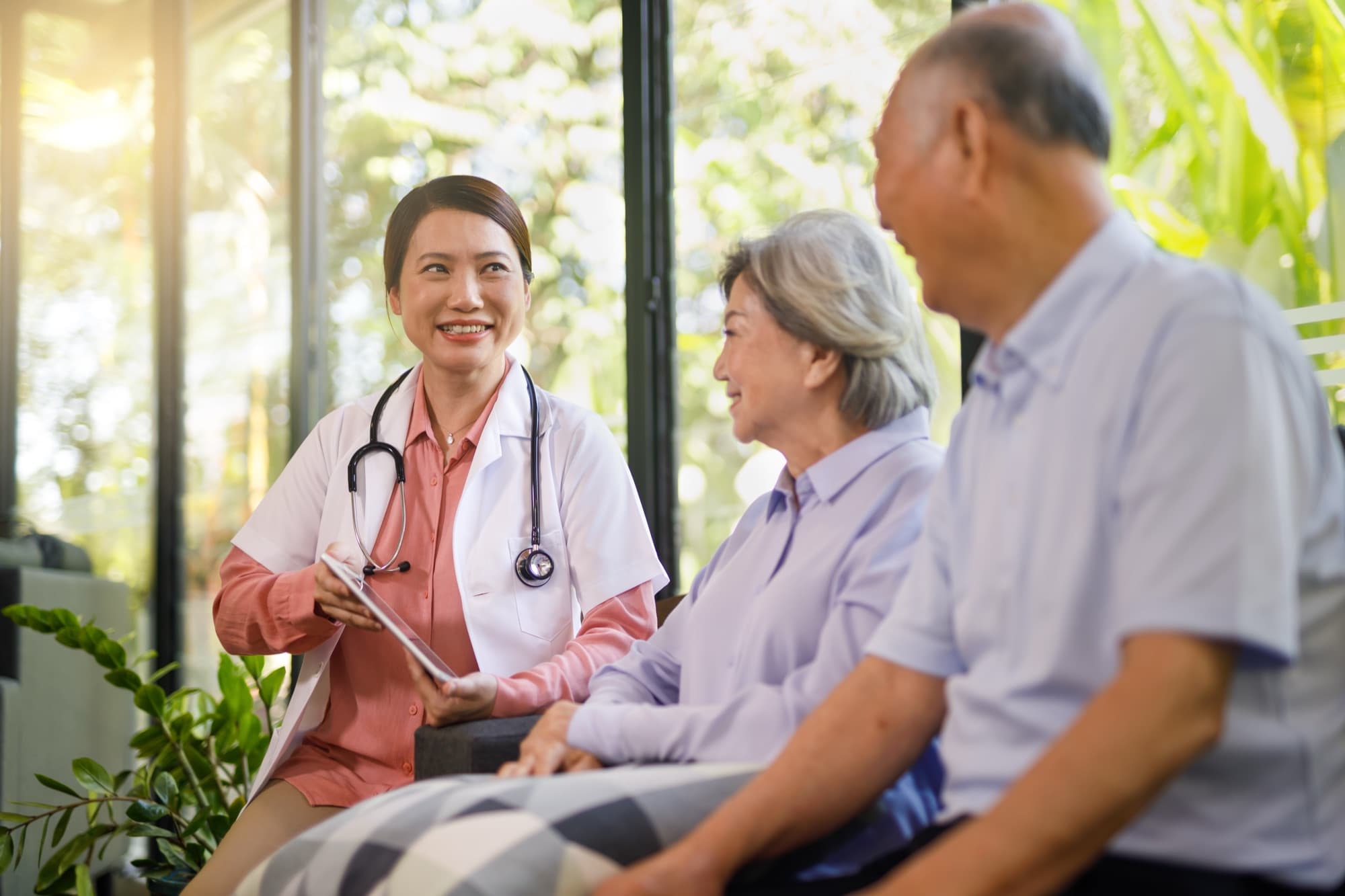 A Care Concierge nurse reviewing care notes on a tablet with an elderly couple at home
